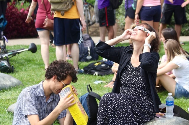 Kyle Posey views a projected image of the partial eclipse through a pinhole camera while Lisa Posey uses special safety glasses at the Arboretum on the afternoon of Aug. 21, 2017