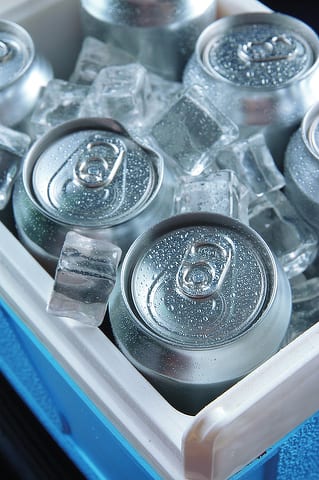 State College - Metal cans of beer with ice cubes in mini refrigerator, close up