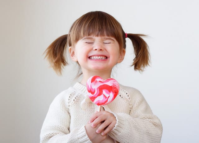 State College - Giddy young girl with a heart-shaped lollipop
