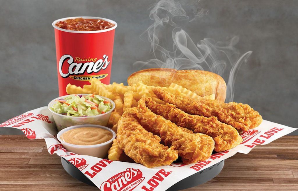 Image of raising cane's cup, and dish with chicken fingers, cup of sauce, cup of cole slaw, crinkle-cut fries and Texas toast