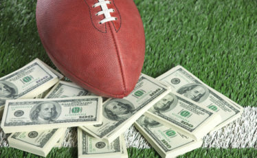 football on field with a pile of money