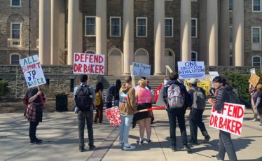 Protesters hold signs in support of Oliver Baker outside of Penn State's Old Main building