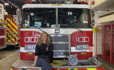 firefighter sarah kollat sits in front of an Alpha Fire Company truck