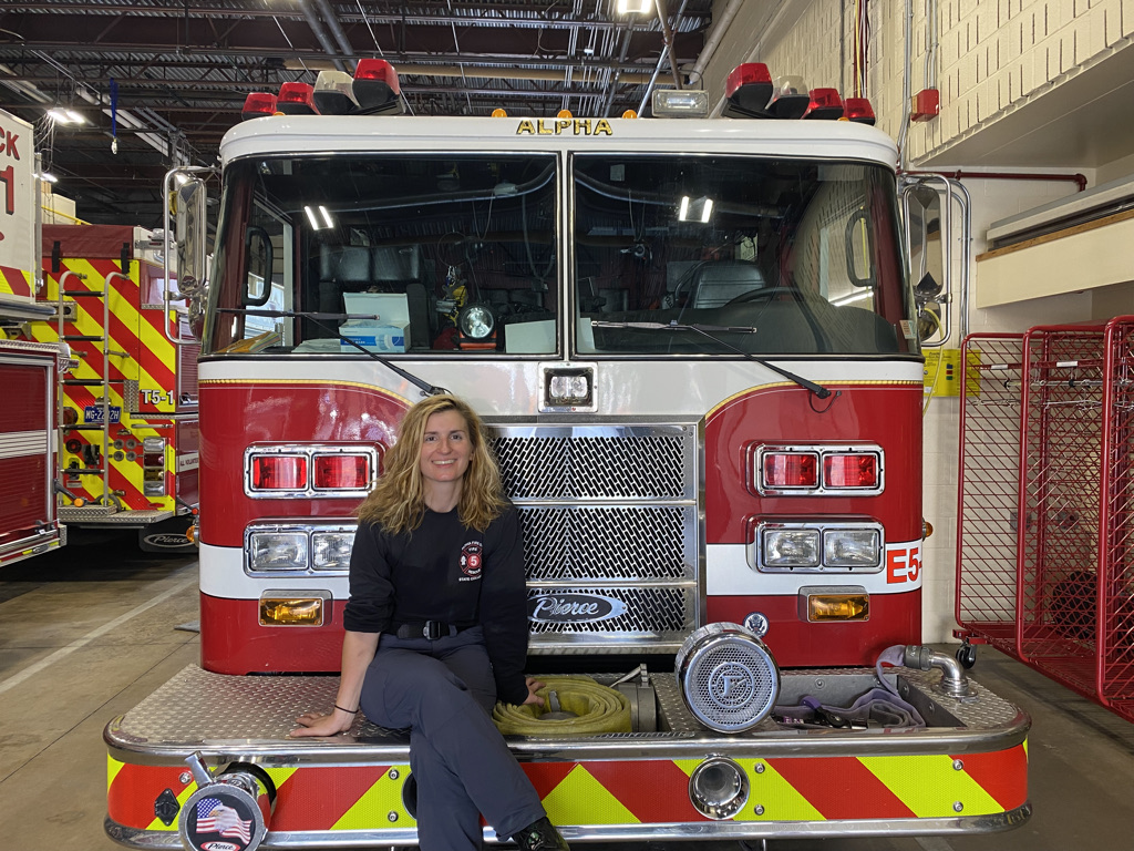 firefighter sarah kollat sits in front of an Alpha Fire Company truck