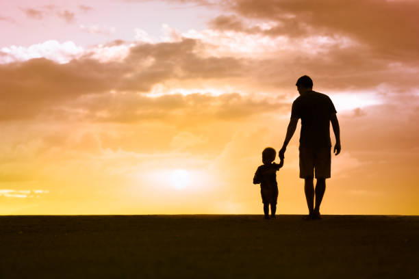 State College - Loving father walking side by side with son holding hands.