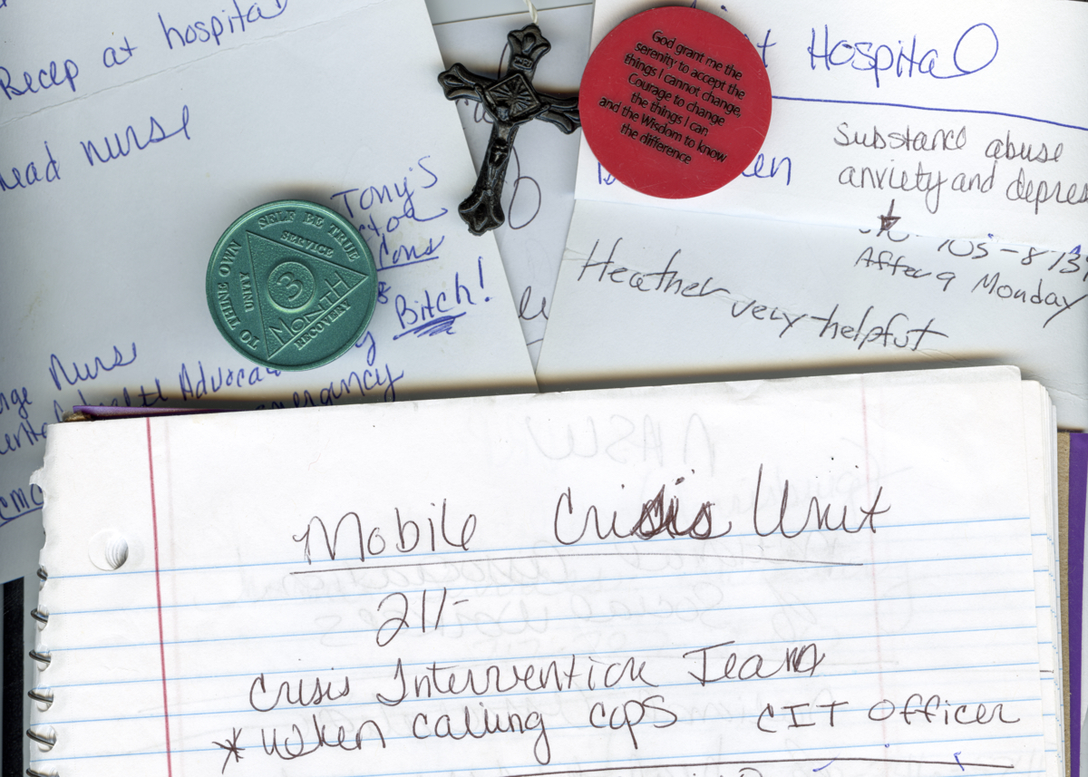 A photo of a notebook, paper, a cross and sobriety chips.