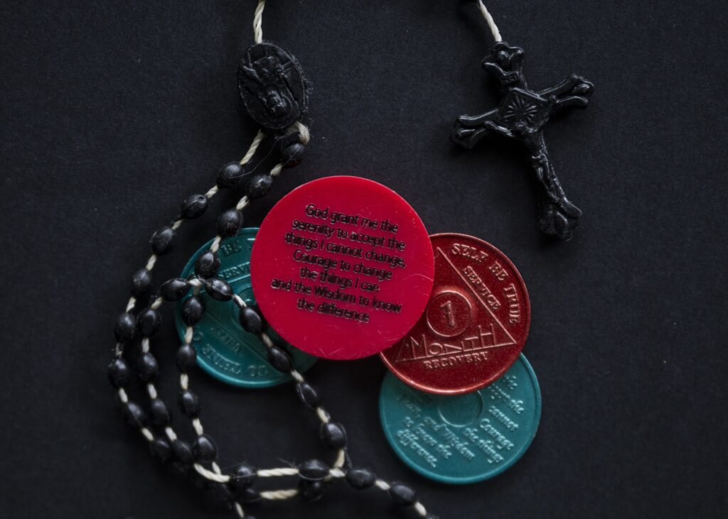 A photo of a rosary and sobriety chips