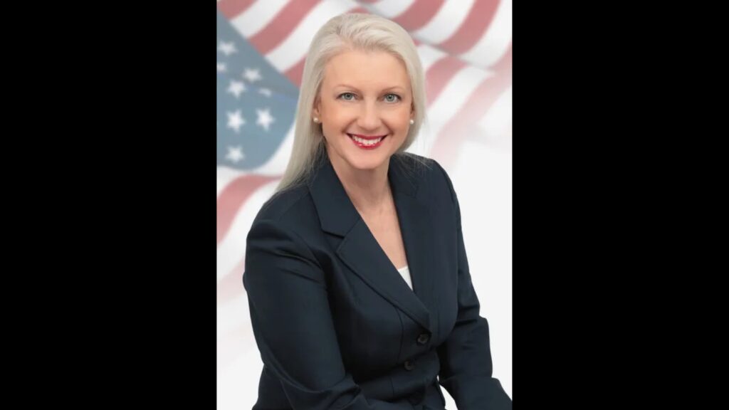Attorney Maria Battista in front of American flag background