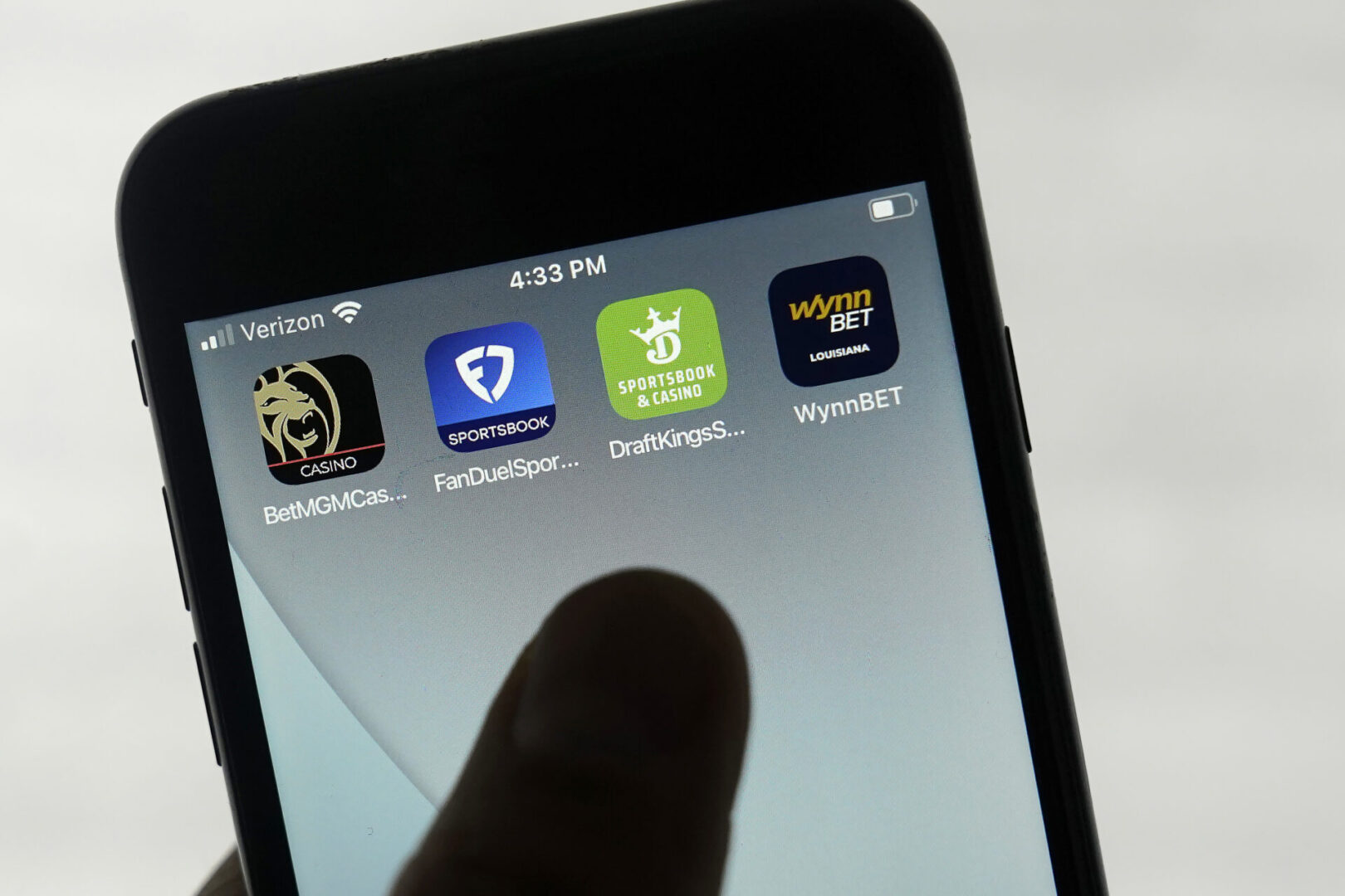 FanDuel, DraftKings, and other online gambling apps are displayed on a phone.