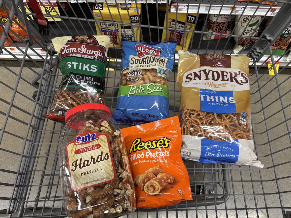 Assorted pretzel varieties placed in a shopping cart at Acme.