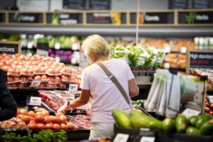 A woman browses produce at a grocery store.