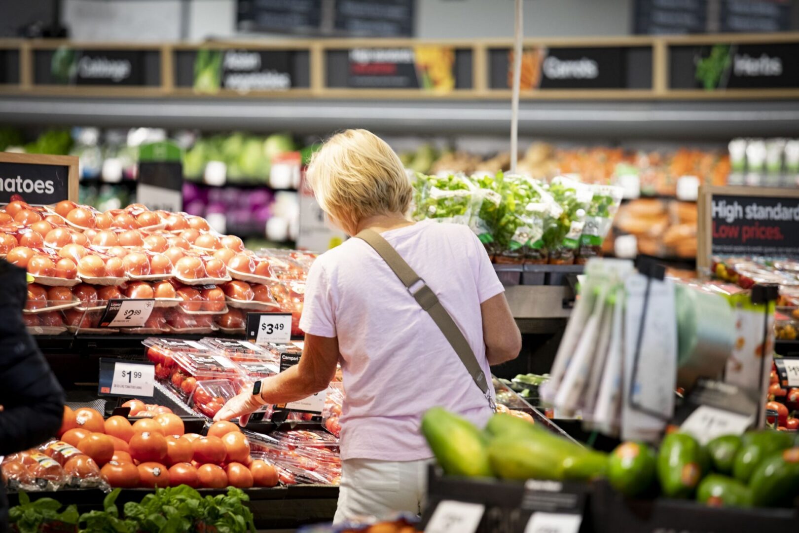 A woman browses produce at a grocery store.