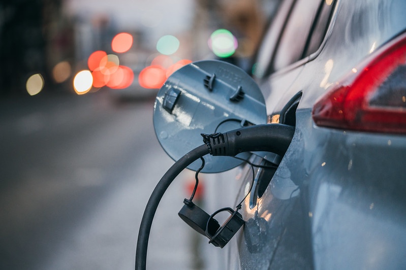 Close-up of an electric car charging. Traffic lights in a blurry background.